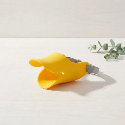 Muselière pour chien jaune avec sangle grise, proche d’une plante, indiquant un accessoire de sécurité pour chiens (Muselière Chien / Tinour).